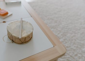 A childrens drum placed on a wooden table in a cozy playroom setting.